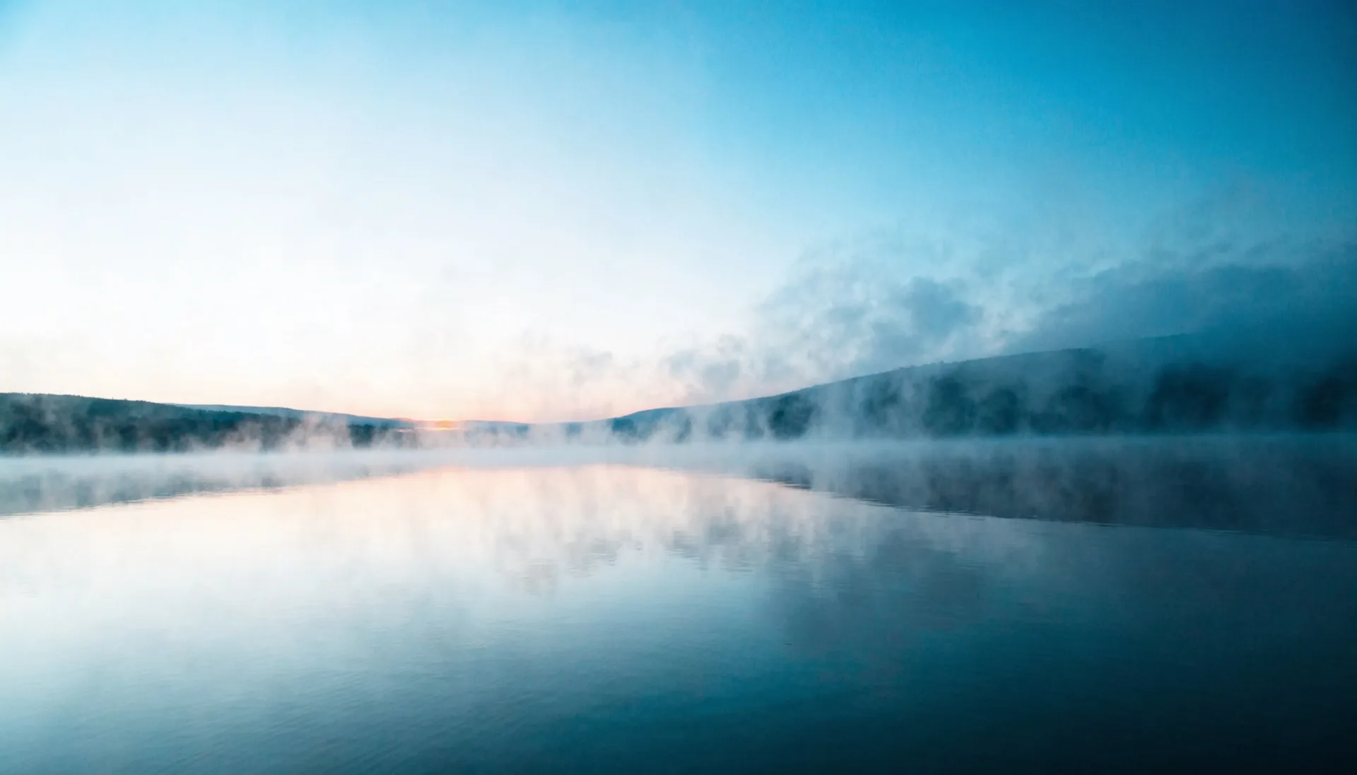 Lac calme au lever du jour, brume légère, tons bleus apaisants